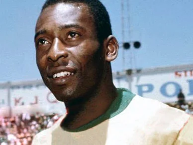 Pelé i Brasiliens gula landslagströja med grön krage, leende på en fullsatt arena