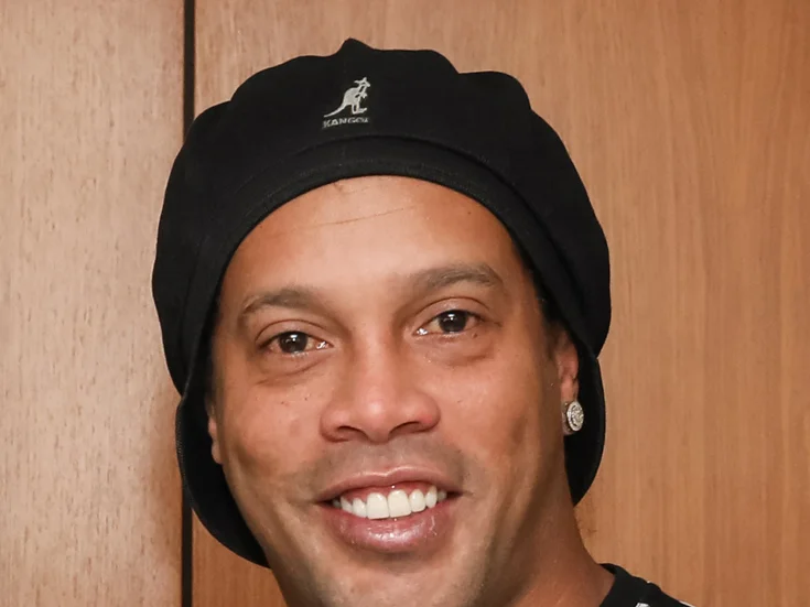 Ronaldinho leende i närbild, bär svart mössa och diamantörhänge
