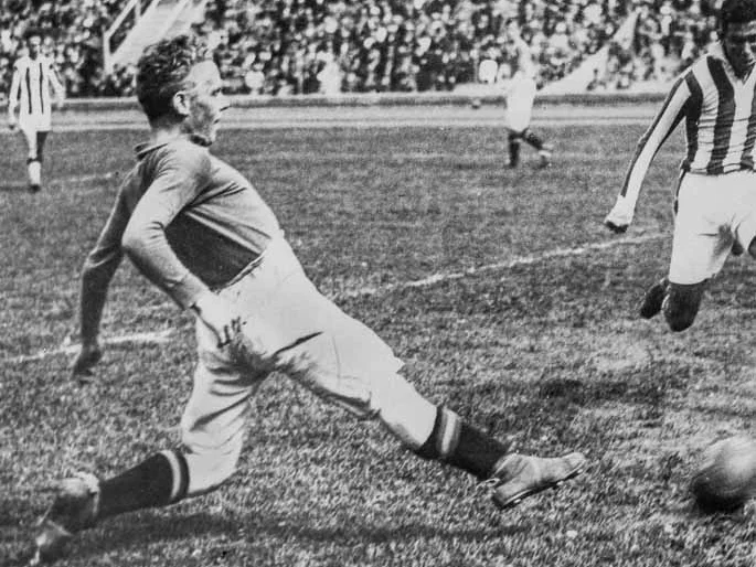 Sven Rydell i full fart mot bollen i en match 1924, med fullsatt läktare i bakgrunden