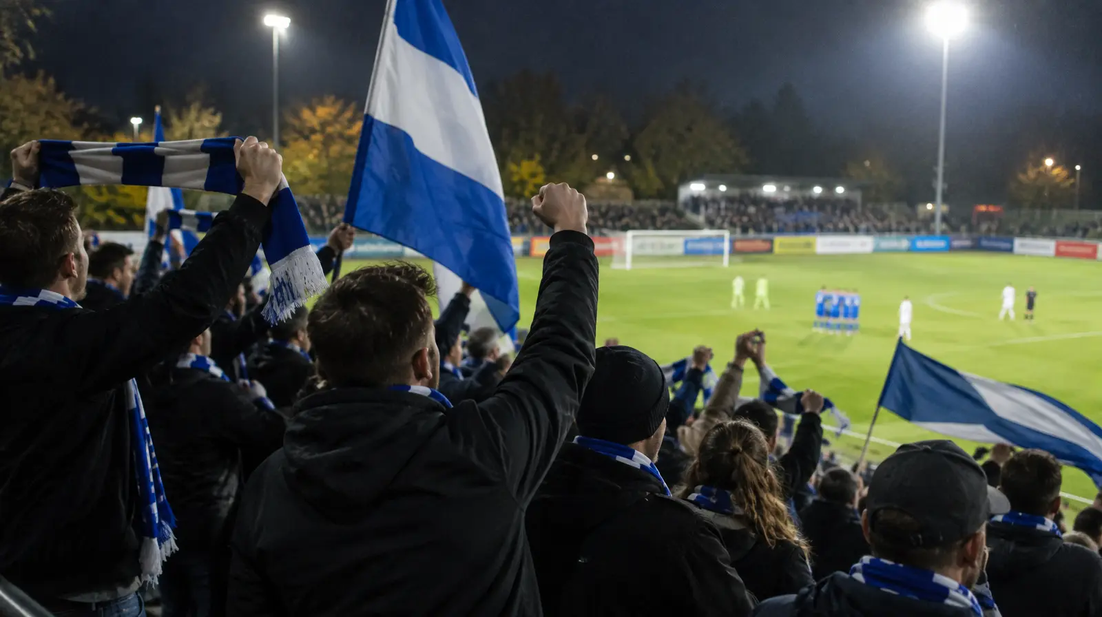 Bortasupportrar jublar på läktaren i kvällsljus